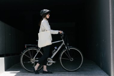 Eko çanta ya da pamuklu çanta taşıyan bir kadın şehirde bisiklet sürerken