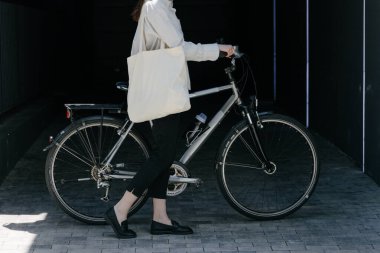 Eko çanta ya da pamuklu çanta taşıyan bir kadın şehirde bisiklet sürerken