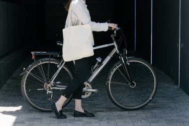 Eko çanta ya da pamuklu çanta taşıyan bir kadın şehirde bisiklet sürerken