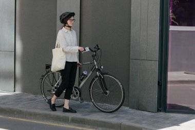 Eko çanta ya da pamuklu çanta taşıyan bir kadın şehirde bisiklet sürerken