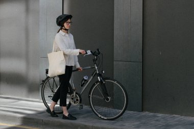 Eko çanta ya da pamuklu çanta taşıyan bir kadın şehirde bisiklet sürerken