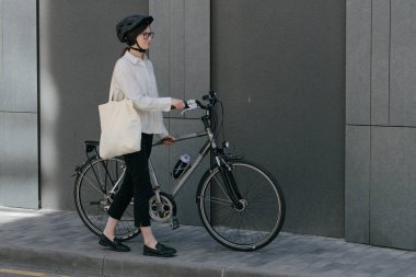 Eko çanta ya da pamuklu çanta taşıyan bir kadın şehirde bisiklet sürerken