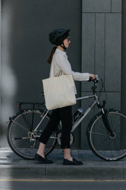 Eko çanta ya da pamuklu çanta taşıyan bir kadın şehirde bisiklet sürerken