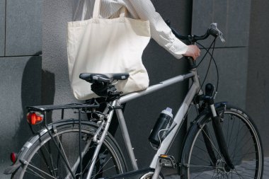 Eko çanta ya da pamuklu çanta taşıyan bir kadın şehirde bisiklet sürerken