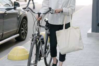 Eko çanta ya da pamuklu çanta taşıyan bir kadın şehirde bisiklet sürerken