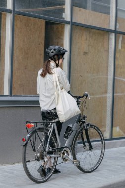 Eko çanta ya da pamuklu çanta taşıyan bir kadın şehirde bisiklet sürerken
