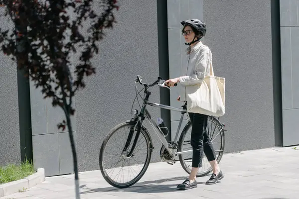 Eko çanta ya da pamuklu çanta taşıyan bir kadın şehirde bisiklet sürerken