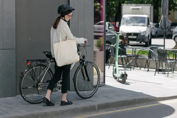 Eko çanta ya da pamuklu çanta taşıyan bir kadın şehirde bisiklet sürerken