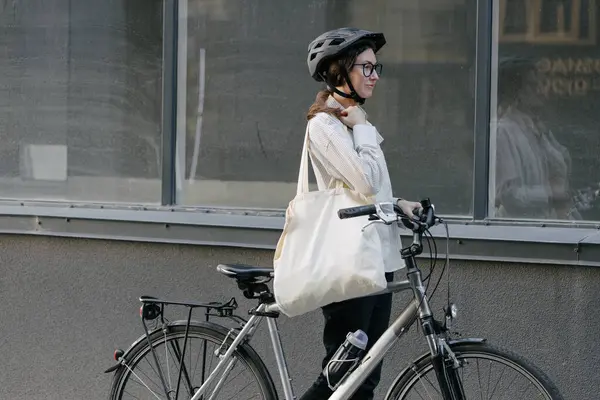 Eko çanta ya da pamuklu çanta taşıyan bir kadın şehirde bisiklet sürerken
