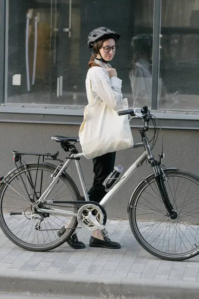 Eko çanta ya da pamuklu çanta taşıyan bir kadın şehirde bisiklet sürerken