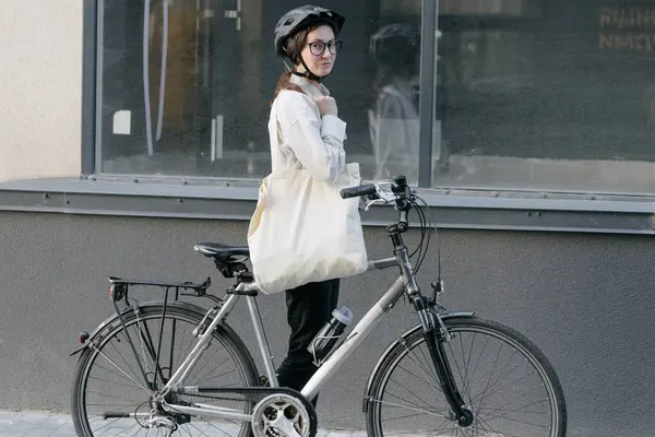 Eko çanta ya da pamuklu çanta taşıyan bir kadın şehirde bisiklet sürerken