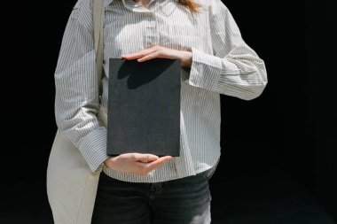 Model için elinde siyah boş bir kitap kapağı tutan kadın.