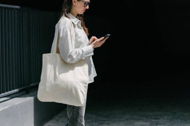 Beyaz çantalı bir kadın şehirde yürüyor.