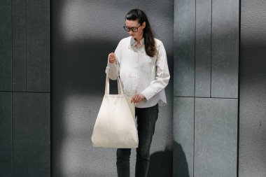 Beyaz çantalı bir kadın şehirde yürüyor.