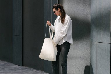 Beyaz çantalı bir kadın şehirde yürüyor.