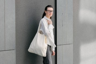 Beyaz çantalı bir kadın şehirde yürüyor.