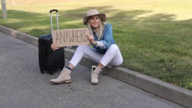 Yorgun bir kadın, umarım boş bir yolun kenarında elinde bavul ve karton posterle bekleyen bir araba bekliyordur. Kadın şehirden kaçıp bir yerlere gitmiş. Seyahat, özgürlük, otostop, tatiller.