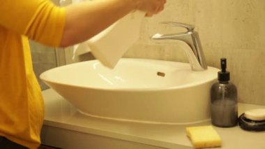 Banyo musluğu yüzeyinde kadın el spreyi deterjanı. Sonra da süngerle ovala. Kadın ev hanımı tuvalette kirli mobilyaları temizliyor. Lavabo ve musluğu temizleyiciyle siliyorum. Temiz ev kavramı.