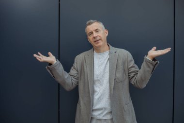 Ciddi, güçlü, kendine güveni olan, el sallayan, kameraya bakan, mavi duvara karşı ne yapacağını bilmeyen bir adam. Meslek ve serbest meslek. Reklam metni için yer. Boşluğu kopyala