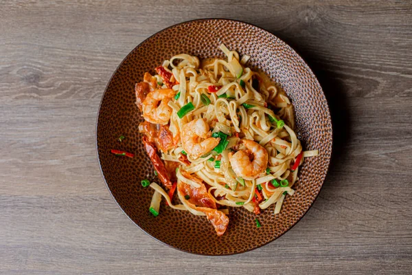 Juicy, ready to eat, organic, tasty macaroni, spaghetti with basil, onion, sauce, seafood, meat, shrimps and tomatoes served on plate on wooden table. Cafe and restaurant. Top view, above, copy space