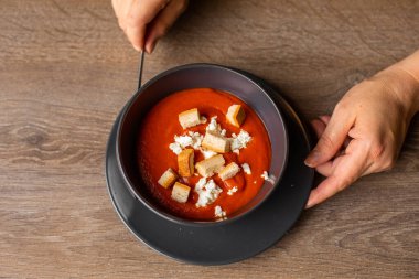 Masanın arka planında izole edilmiş siyah domates çorbası kasesi. Çıtır krakerli gazpacho servisi. Gurme, Avrupa yemekleri, güzel servis..