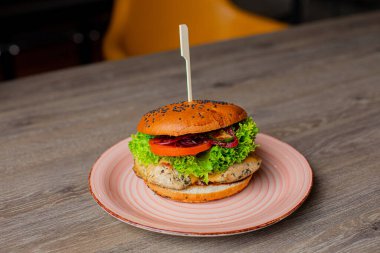 Lokantada tabağında şiş olan lezzetli, taze hamburgerleri yakın çekim. Sığır eti ya da ızgara tavuk burger, kabuklu çörek, siyah susam, domates ve maydanoz, salata pirzolası ve sos, tabakta sunulur.