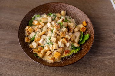 Lezzetli, taze, sulu, Sezar salatası yemeye hazır tavuk, kızarmış ekmek, salata, marul ve baharat yaprakları ahşap masada. Sağlıklı yaşam tarzı ve beslenme düzeni. Yüksek açı görünümü