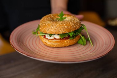 Closeup plate with juicy appetizing vegan burger isolated on wooden table background. Serving of savory hot sandwich for dinner. Fast food cafe, nutrition without meat, restaurant dish, meal.