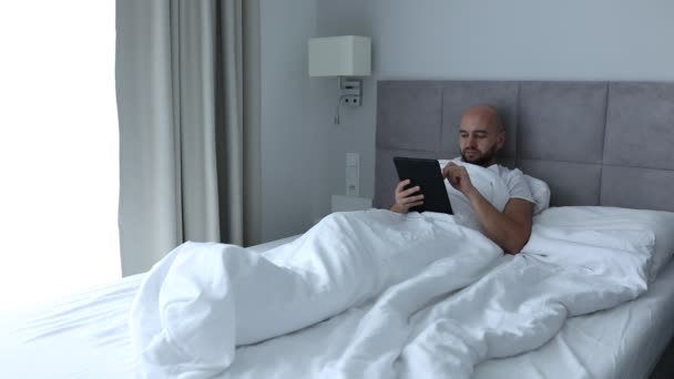 Mature Berjenggot Tersenyum Pria Menggulung Mengetik Layar Tablet Digital Berbaring — Stok Video