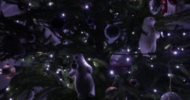 Close-up of New year Christmas tree decorated with glowing flashing lights string garland, white teddy bears, toys, baubles of different sizes. New year, Christmas, holiday, decoration, celebration.