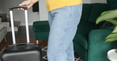 Kot pantolonlu, bavul sapını çekip giriş kapısına taşıyan tanınmamış bir kadının video animasyonu. Dışarı çıkmak, yer değiştirme ve göç, yeni bir yere ve daireye kaçmak. 4k çözünürlüğü