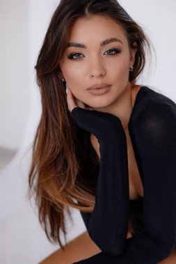 Magnificent sexy woman seductively touching face with hands. Female portrait closeup. Gorgeous brown haired woman with passion posing in studio in black bodysuit. Sexual energy, femininity.