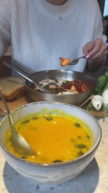 Cream of roasted pumpkin soup. Close-up view of person mixing ready pumpkin cream soup using spoon. Front view. Verticale video. 4k footage