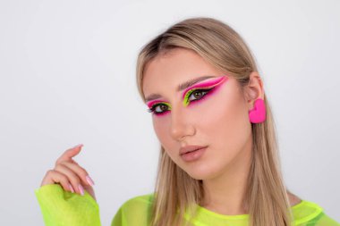 Moda modelinin yüzünde parlak neon makyajın portresi. Güzellik anlayışı. Makyöz mesleği. Modern moda trendleri. Yaratıcı bir imaj. Pembe ve açık yeşil tonların birleşimi. 