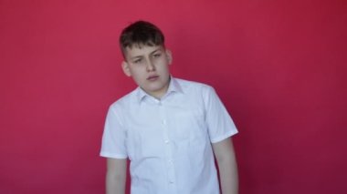 Büyük sürpriz. Kısa kollu beyaz gömlekli 12 yaşındaki genç çocuk stüdyoda kırmızı arka planda çok şaşırdı. Sürpriz ve sürpriz. Yüz ifadeleri ve duygular. Tam HD görüntüler.