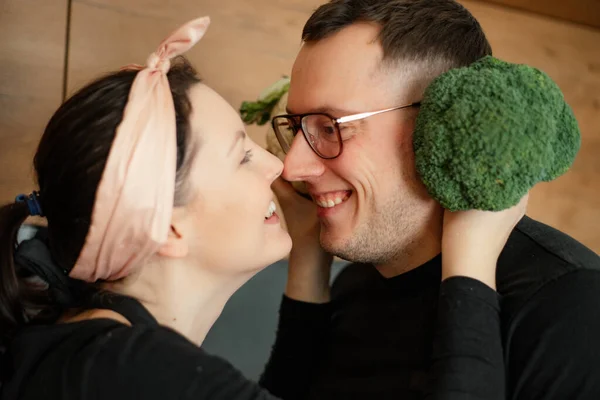 stock image Close up smiling, humorous, loving couple of mature man in eyewear and woman in headband, face to face, look at each other. Wife holding cauliflower cabbage as ears near husband face. True love family