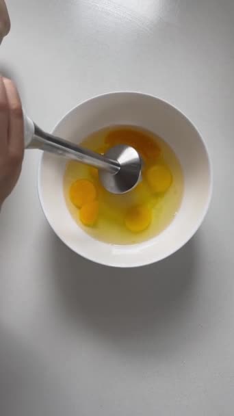 女性の手は泡になるまでボウルに浸漬ミキサーで生の卵を打ちます 垂直調理ビデオのトップビュー シャルロットケーキ アップルパイの伝統的なレシピ 自家製デザート シャーロット料理 — ストック動画