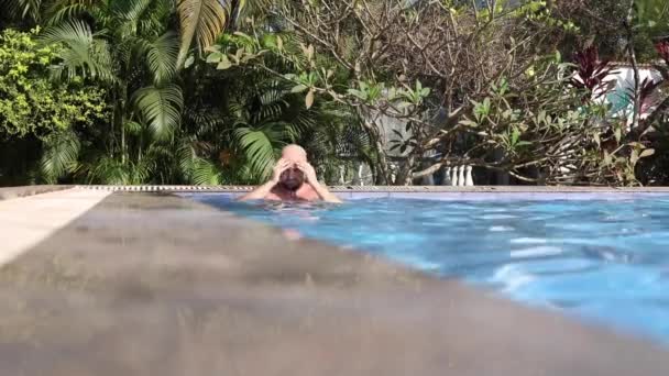 Olgun Kel Adamın Mavi Yüzme Havuzunda Palmiye Ağaçlarına Karşı Hava — Stok video