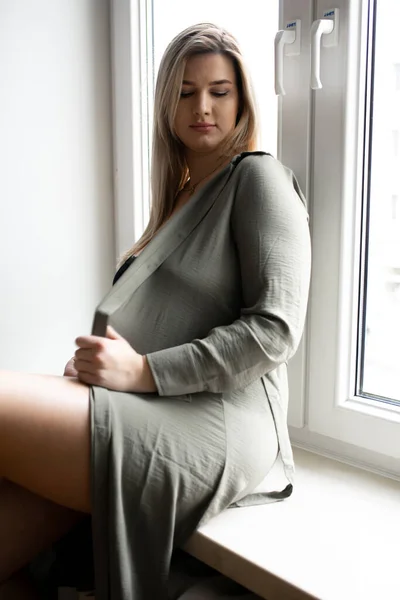Портрет Привлекательной Длинноволосой Беременной Женщины Серой Длинной Рубашке Сидящей Подоконнике — стоковое фото