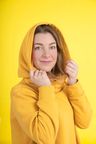 Portrét Atraktivní Čtyřicetileté Ženy Žluté Mikině Kapucí Hlavě Žlutém Pozadí — Stock fotografie