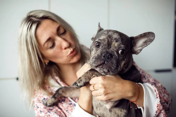 Funny French bulldog listens attentively to what his owner says in his ear. Maintenance and care of dogs. Healthy pets. Happy moments. Positive emotions. Friendship and mutual understanding.