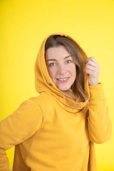 鲜艳的色彩是现代流行的趋势 在演播室里 40岁穿着黄色连帽衫 头戴黄色背景头罩的迷人女人对着摄像机 体育与健康 年度色彩 — 图库照片
