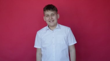 Gute 12 yaşında bir genç neşe, olumlu duygular ve kahkahalar gösteriyor. Stüdyo kırmızı arka plan. Kameraya bakar. Neşe ve rahatlama. Olumlu duygular. Yüz ifadeleri ve jestler. Tam HD görüntüler.