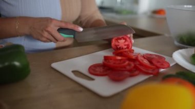Ev yapımı giysiler içinde tanınmayan bir kadın mutfağında taze sebze salatası pişiriyor, domatesleri halka şeklinde kesiyor. Sağlıklı beslenme. Yiyeceklerdeki vitaminler ve eser miktarda elementler. Tam HD görüntüler.