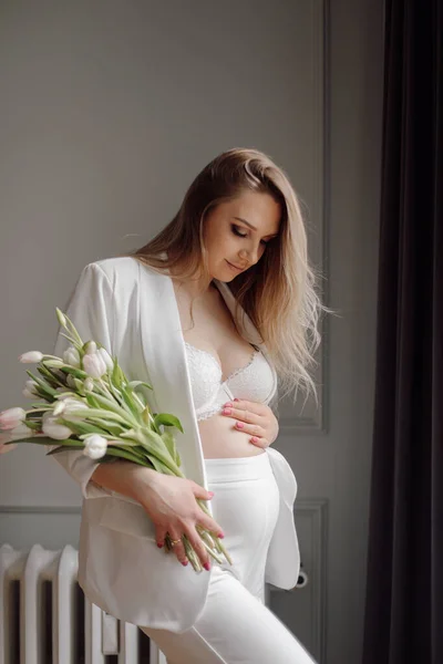 수트를 창밖에 꽃다발을 바라보고 매력적 임신부의 어머니 — 스톡 사진
