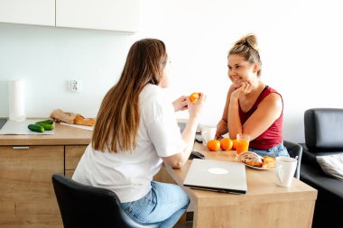 Merkez ofis, başlangıç. İletişim ve anlayış. İki tatlı kız arkadaş mutfakta karşılıklı oturup konuşuyorlar, portakal suyu içiyorlar. Rahatlık ve iş. İş kadını.. 
