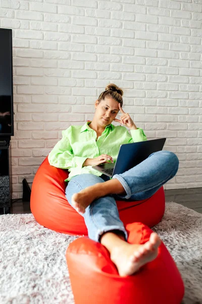 과편안 프리랜서인 여성은 집에서 침착하게 의자에 다리를 컴퓨터로 온라인으로 일하고 — 스톡 사진