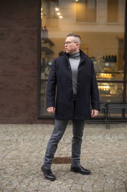 Siyah gözlüklü yakışıklı işadamının portresi. Gri pantolon, kafenin yanında gri kazak. Şehir merkezinde patronu beklerken arkama bakıyorum. 
