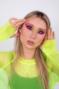 Moda modelinin yüzüne yakın plan parlak neon makyaj. Gençlik ve güzellik kavramı. Sanatçılık. Modern moda trendleri. Yaratıcı bir imaj. Pembe ve açık yeşil tonların karışımı. Kozmetik. 