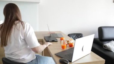 Zaman-yaka. İki kadın birlikte çalışma formatında rahat kıyafetler içinde İnternet 'te çalışıyor, müşterilerle iletişim kuruyor, eğitime katılıyor. Hoş bir atmosfer. Birlikte çalışıyoruz. Güzel ofis. Tam HD görüntüler.